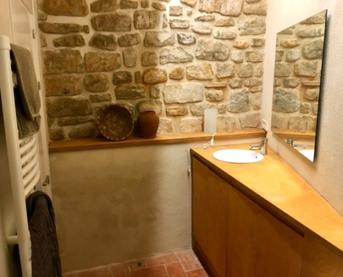 Salle de bain et mur en pierre dans gîte rural